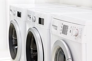 row line of modern white laundry washing machines